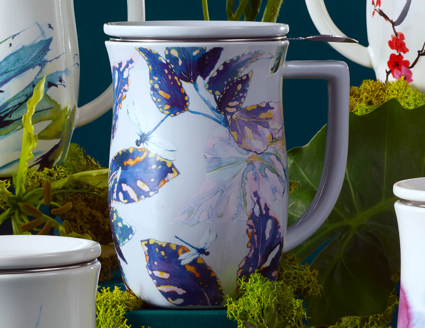 Closeup of the Demoiselle Fiore Steeping Cup, closed, with lid on, laying amongst moss and plants and other Fiore Cups