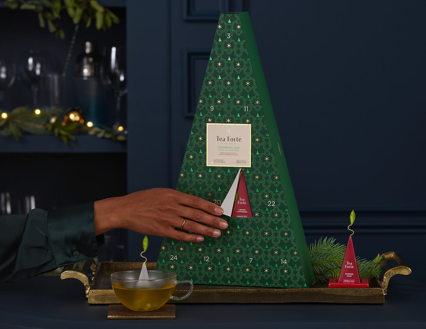 Opening a door of the Warming Joy Herbal Advent Calendar, with cup and tea and infuser on a tray