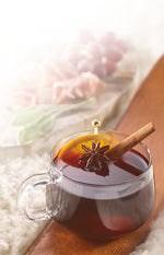 Glass mug of mulled wine with a cinnamon stick on a wooden surface