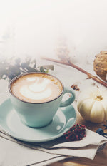 Pumpkin Spice hot latte in a Blue teacup and saucer with white mini pumpkins and a cloth napkin